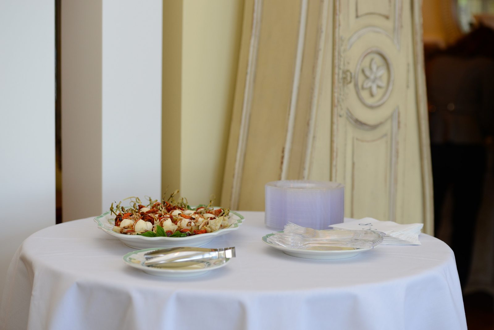 A round table with a plate of appetizers, napkins and a candle (view 1)
