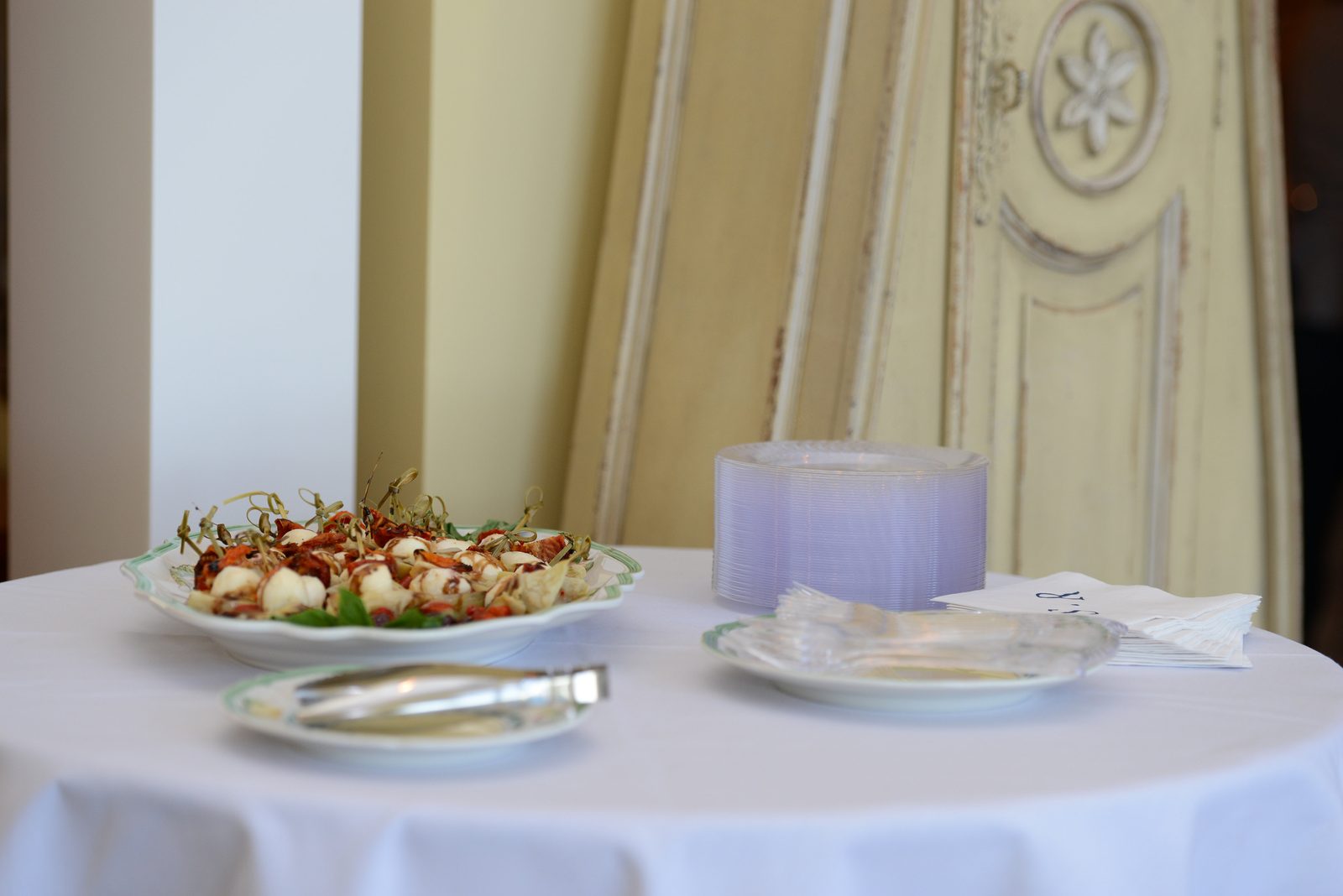 A round table with a plate of appetizers, napkins and a candle (view 2)