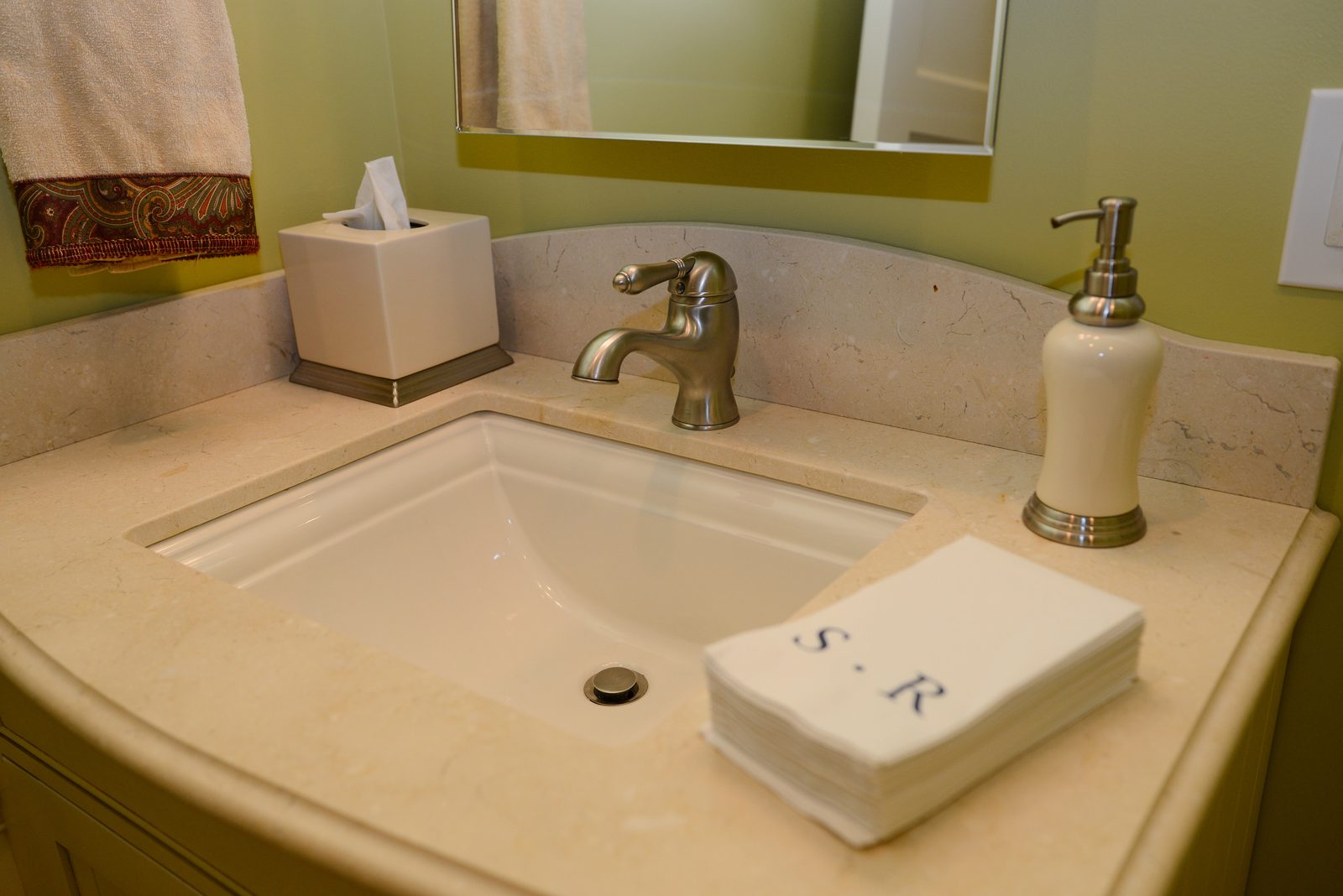 A bathroom basin with monogrammed hand towels and a soap dispenser (view 1)