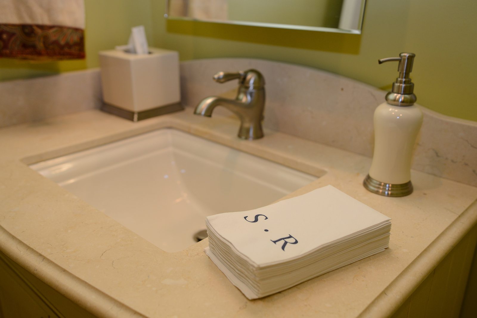 A bathroom basin with monogrammed hand towels and a soap dispenser (view 2)