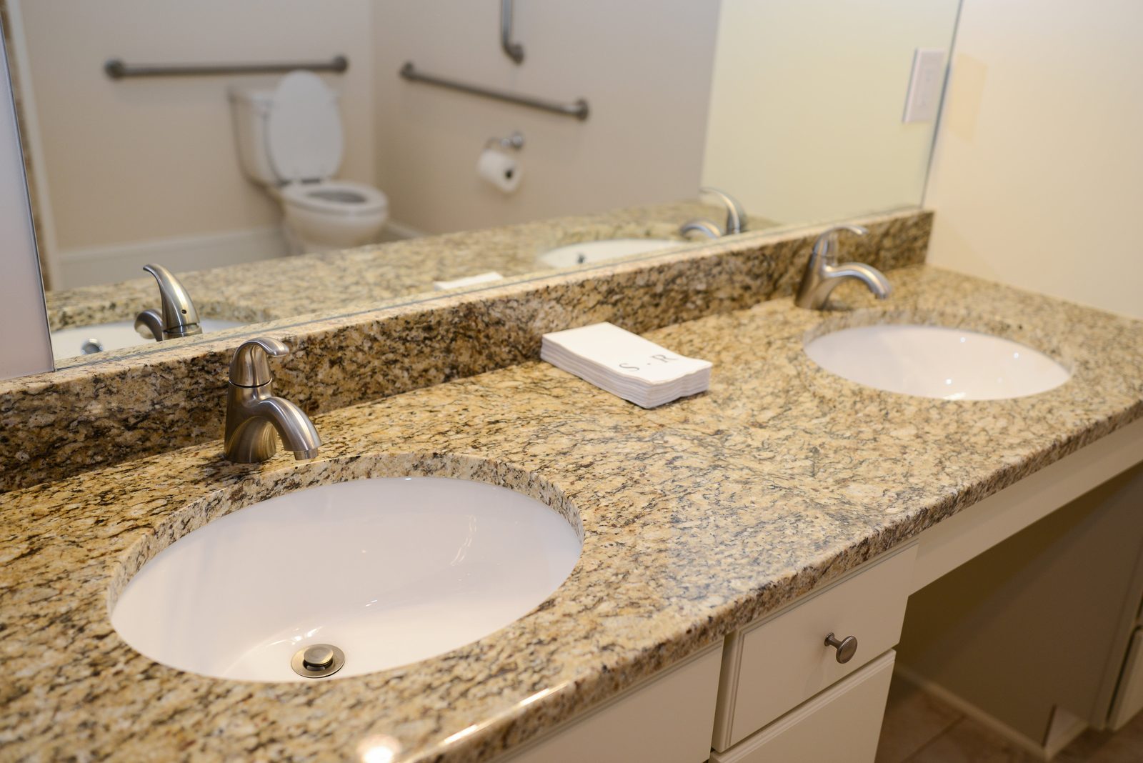 A double vanity with a granite countertop and two mirrors