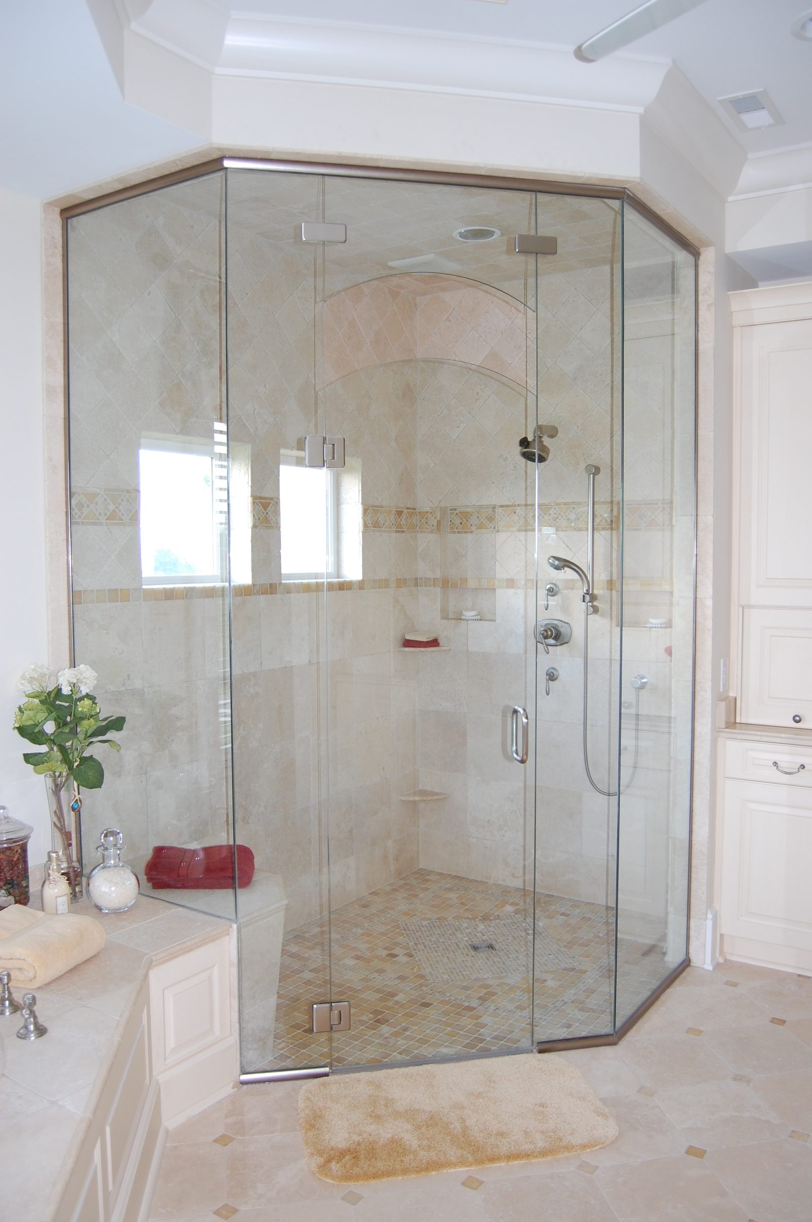 A bathroom with a large angled glass shower enclosure