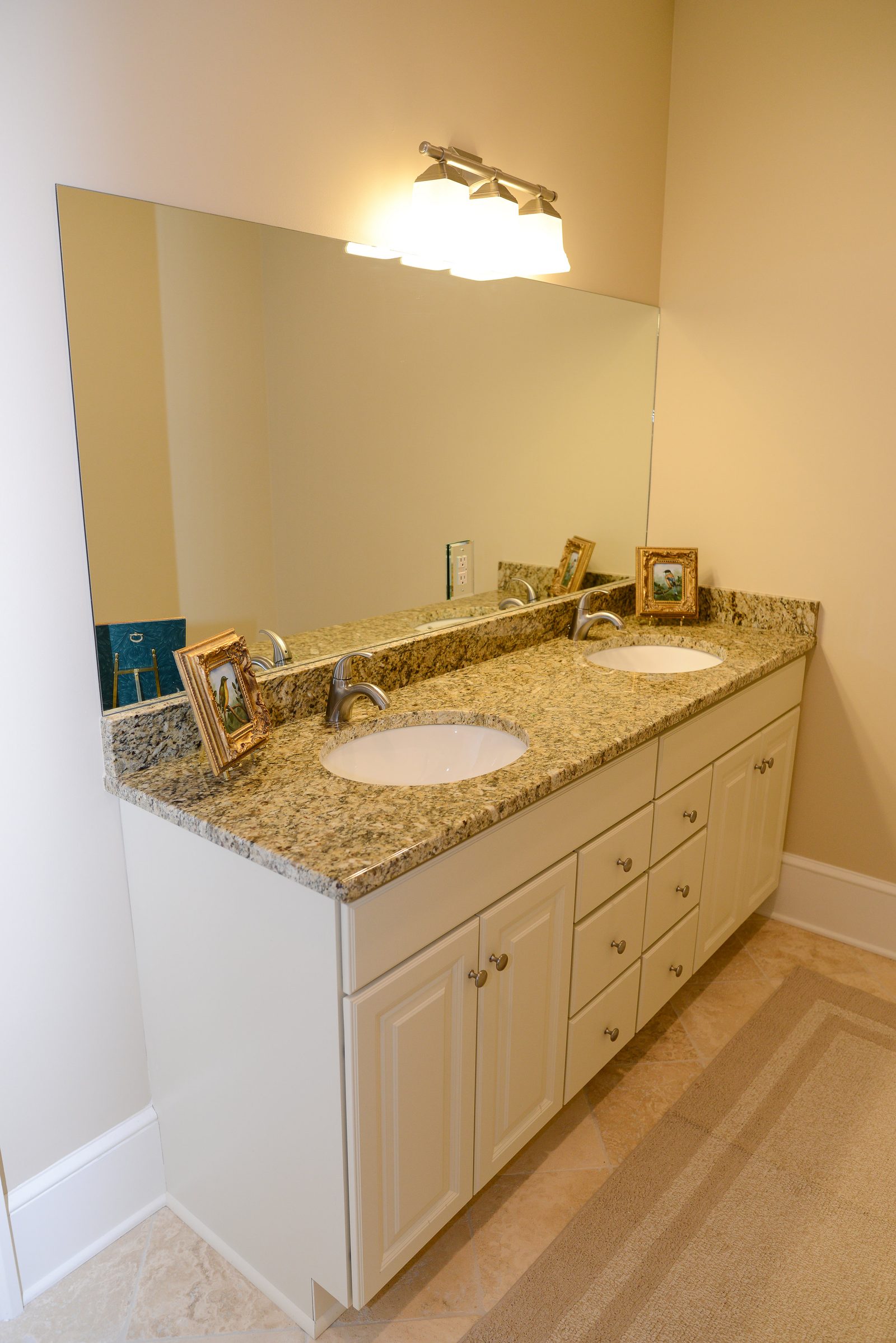 A bathroom vanity with a granite countertop and a wide mirror