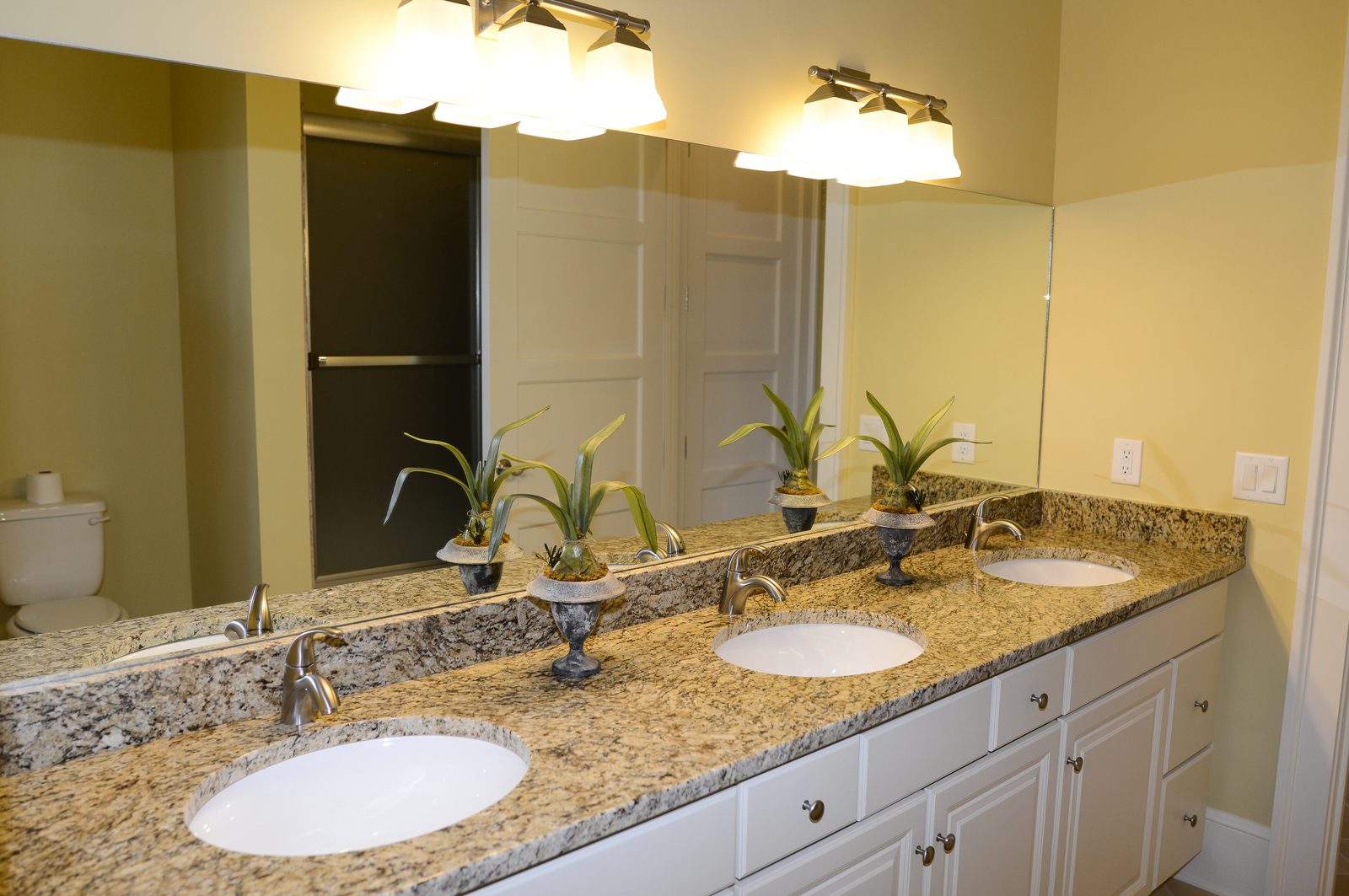 A long bathroom vanity with two basins, granite counter and a full mirror