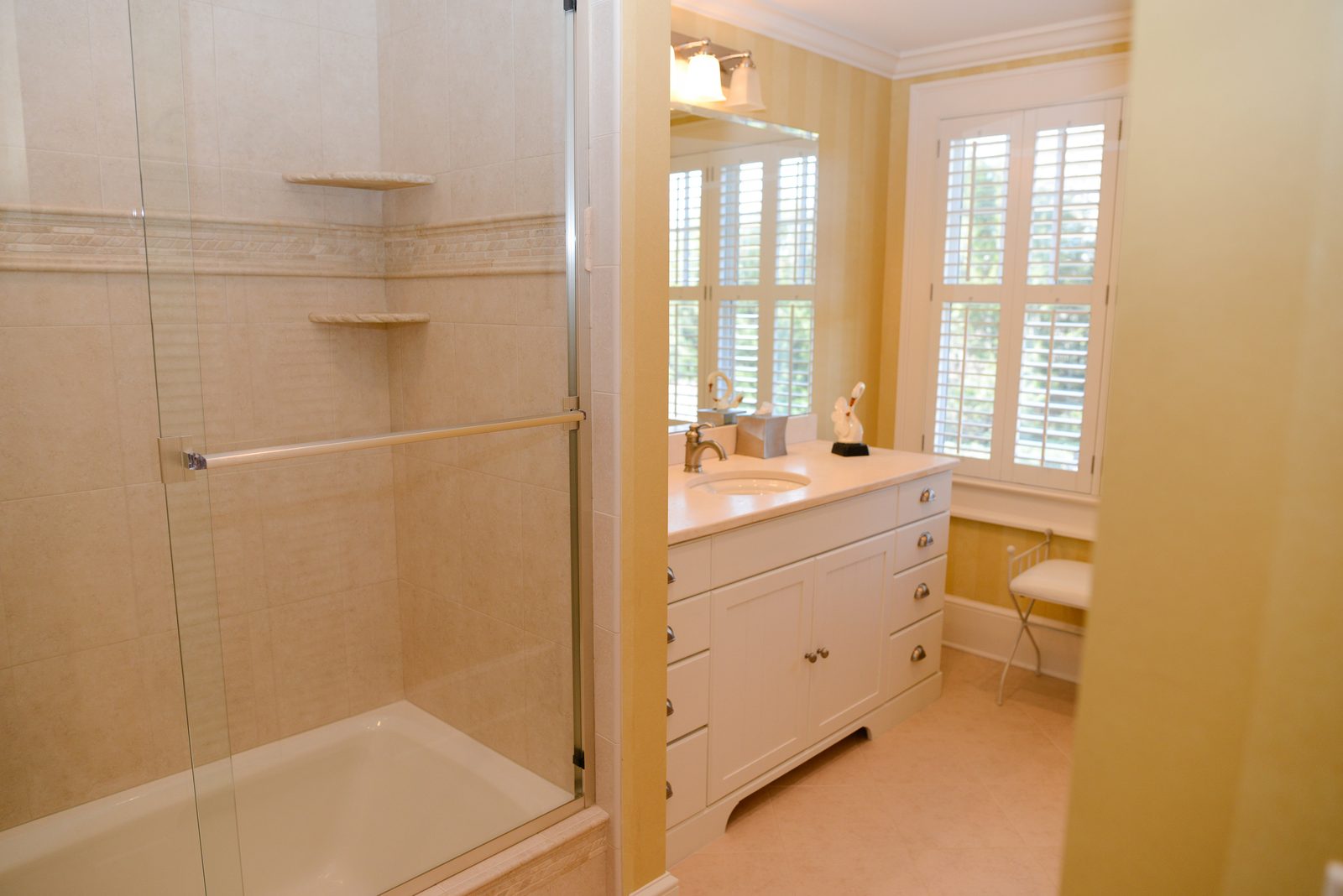 A guest bathroom with a walk-in shower and a white vanity beside a window