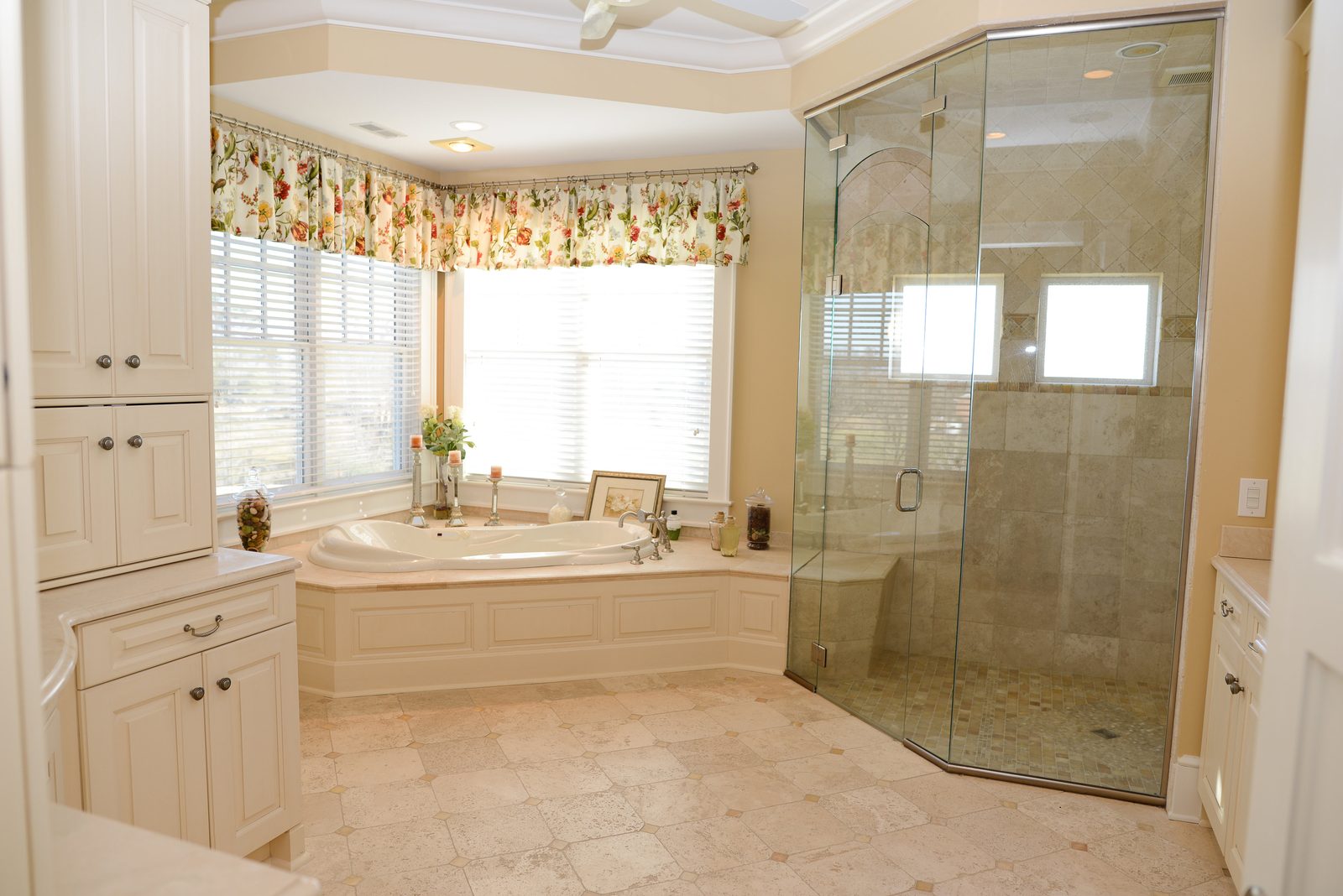 A guest bathroom with a corner soaking tub beneath a curtained window and a glass shower