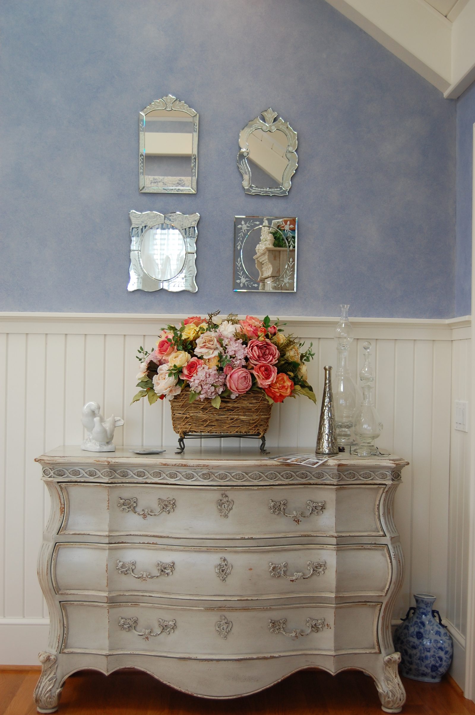 A bedroom with blue checked seating, an iron bed and a painted chest (view 2)
