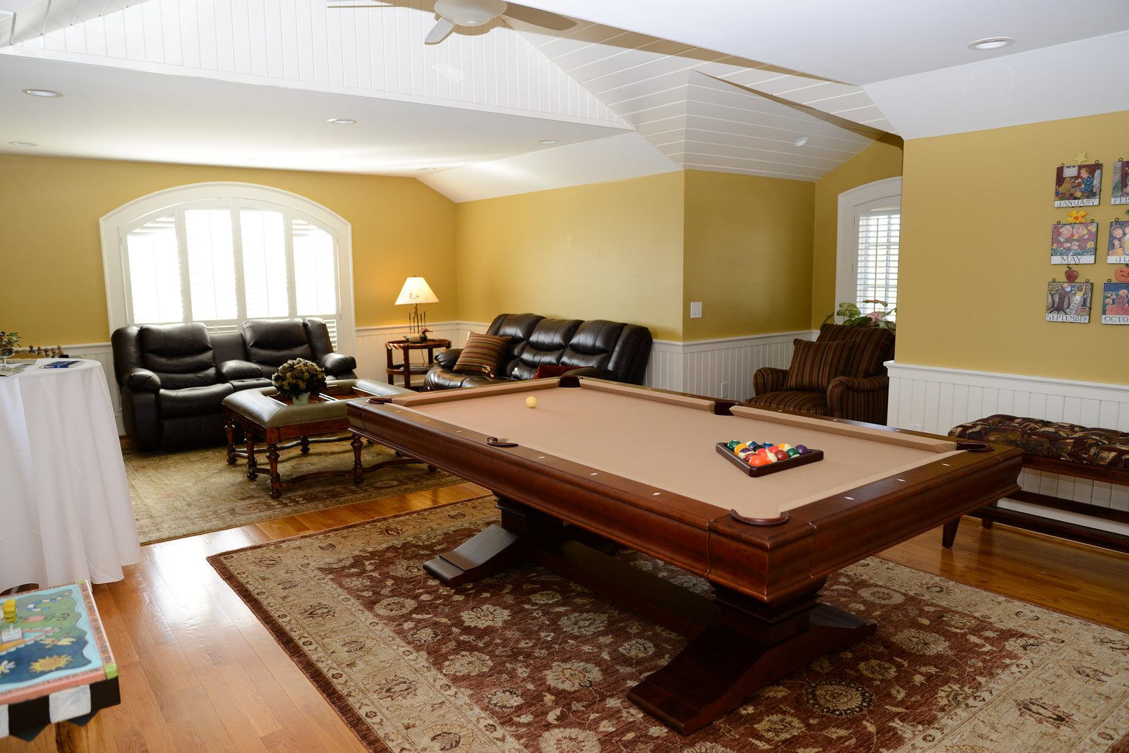 A recreation room with a billiards table, leather seating and a patterned rug