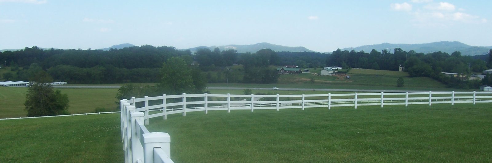 Pasture and white fence line with the distant Blue Ridge Mountains