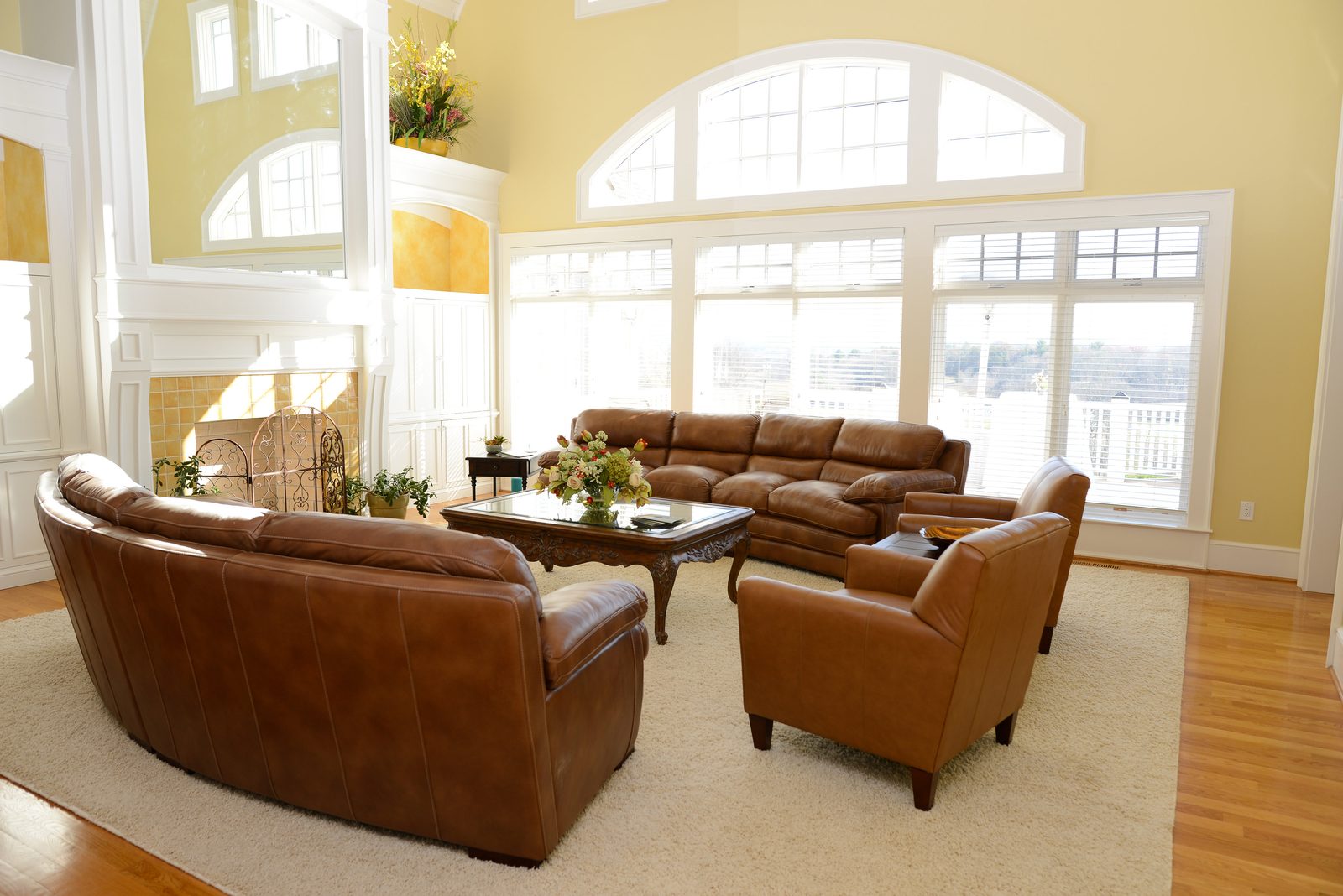 A commons area with leather sofas and armchairs beneath tall arched windows