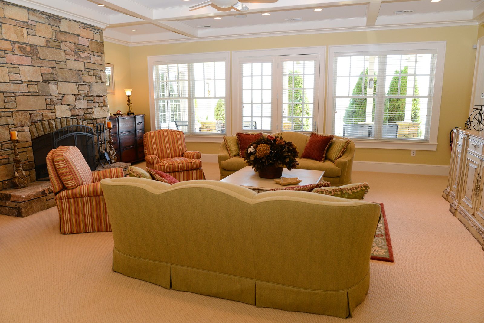 A sitting room with a stone fireplace, upholstered sofas and a wall of windows