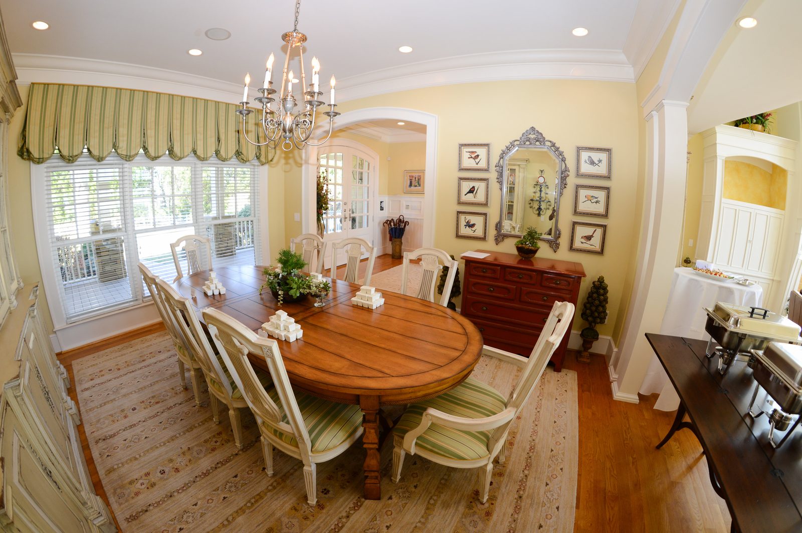 A long dining table set for a group beneath a chandelier