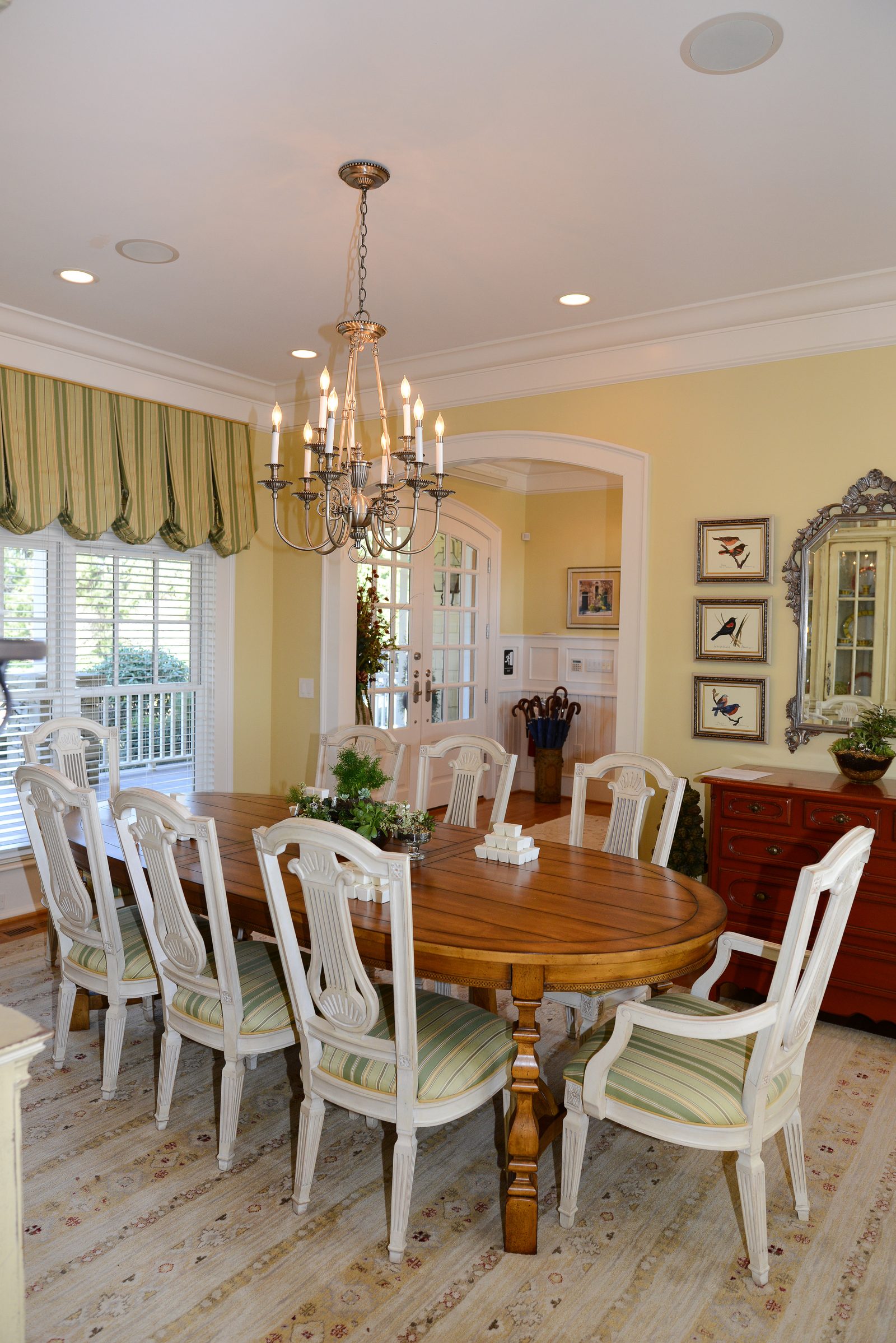 A formal dining room with an oval table, upholstered chairs and a chandelier (view 2)