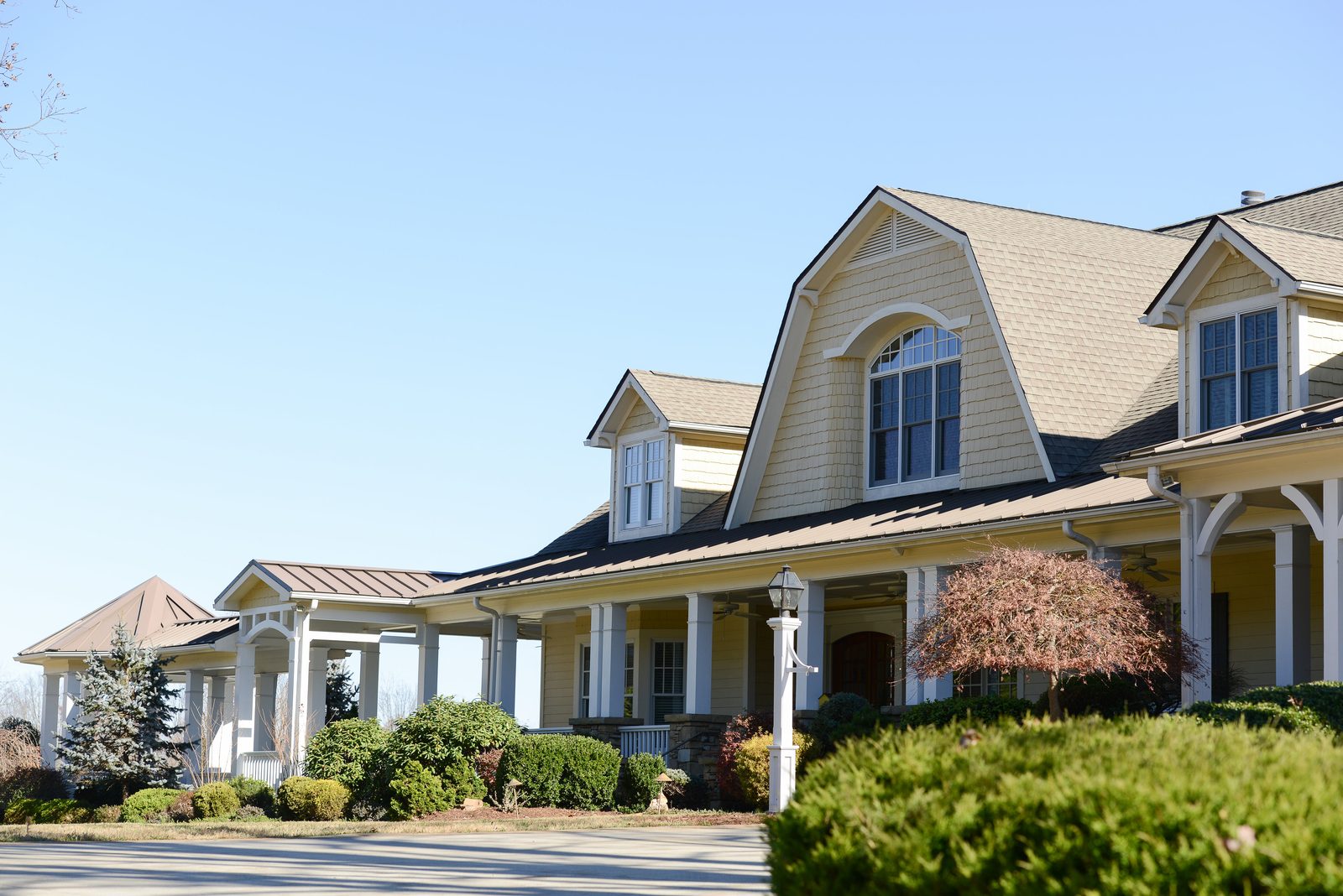The front porch and dormers of the main residence with foundation plantings (view 1)