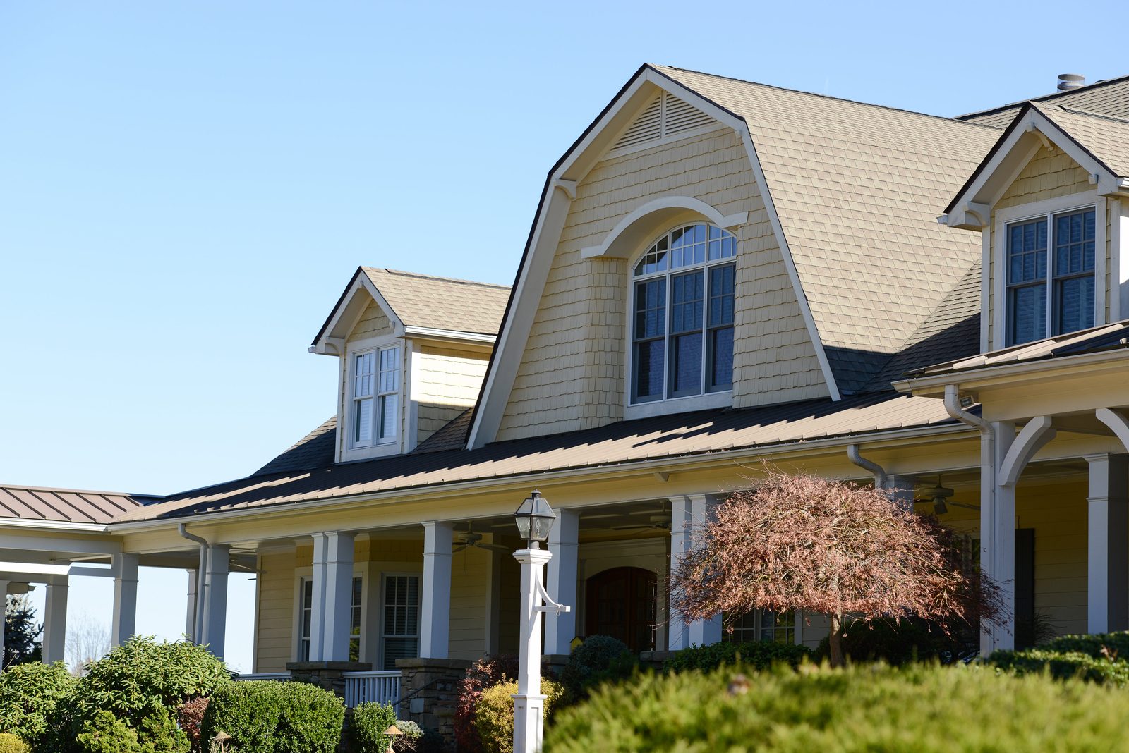 The front porch and dormers of the main residence with foundation plantings (view 2)