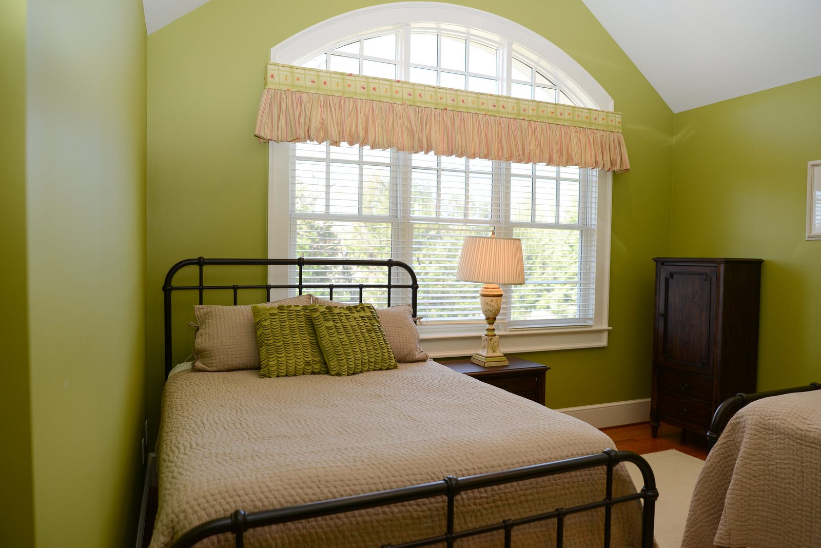 A guest room with an iron bed, green walls and a valanced window (view 1)