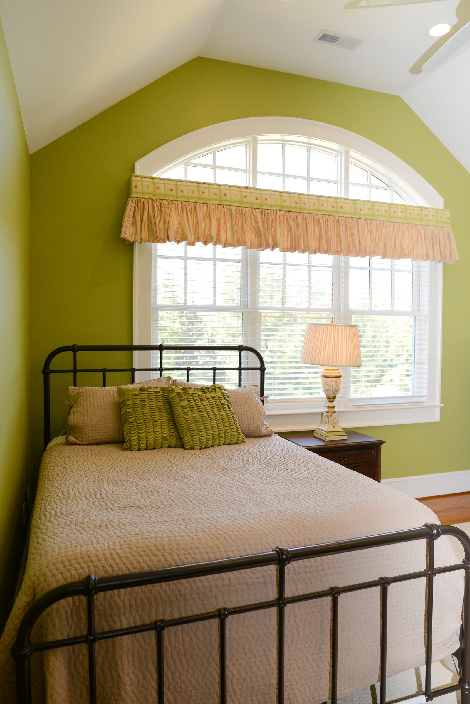 A guest room with an iron bed, green walls and a valanced window (view 3)