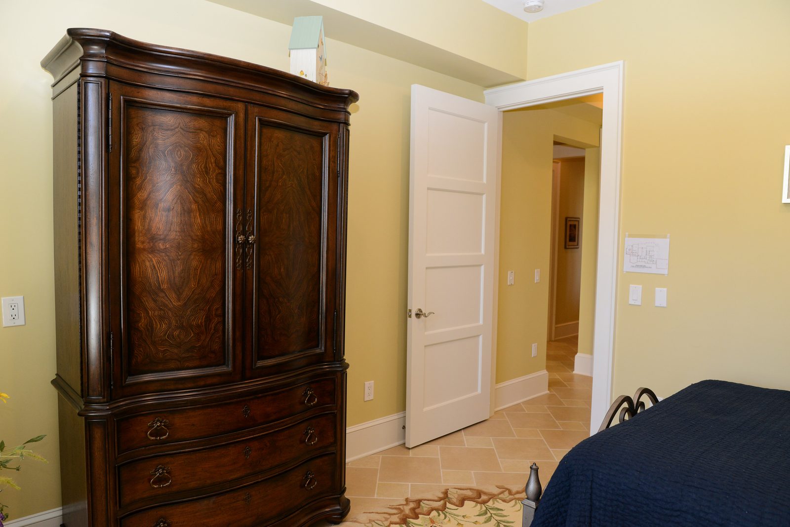 A guest room with an iron bed dressed in navy linens, a lamp and a nightstand (view 7)