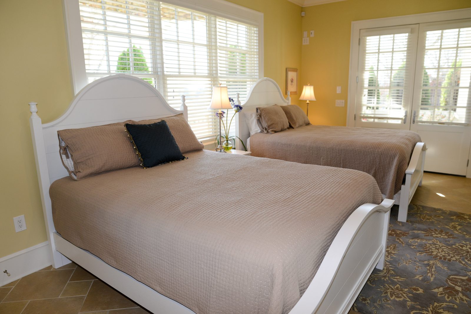 A guest room with two white beds, neutral linens and shuttered windows (view 1)