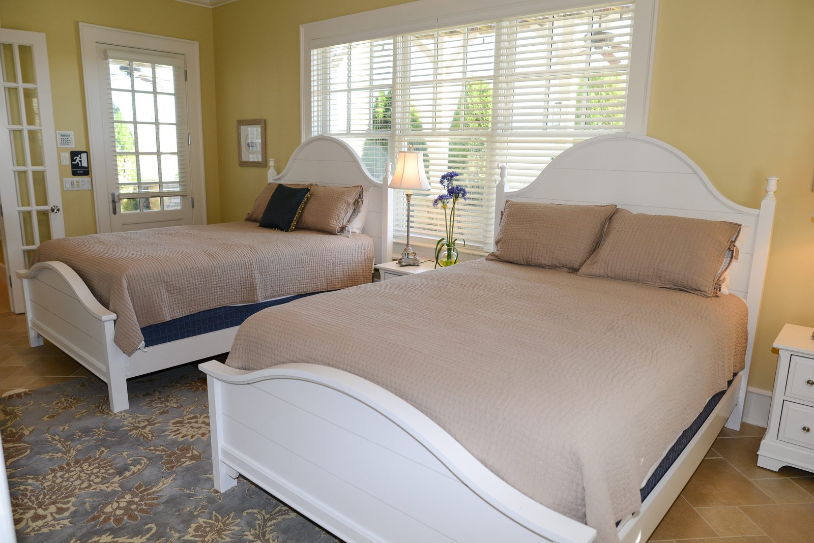 A guest room with two white beds, neutral linens and shuttered windows (view 2)