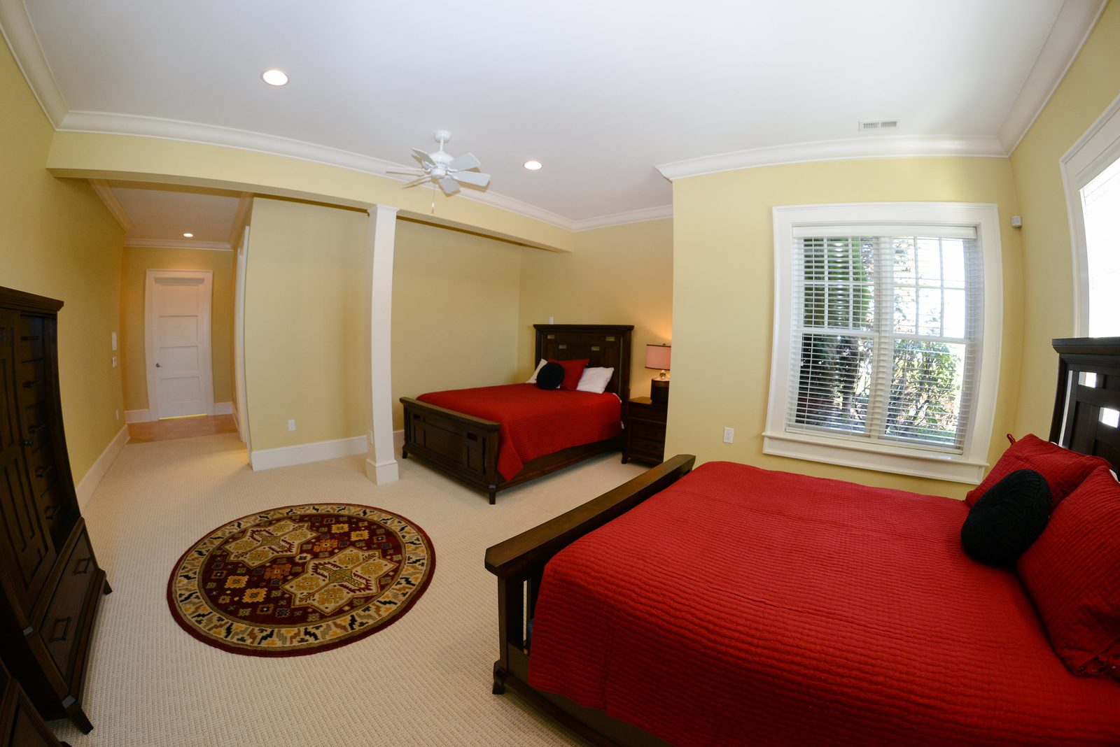 A guest room with red-linened beds, a column detail and a round area rug (view 1)