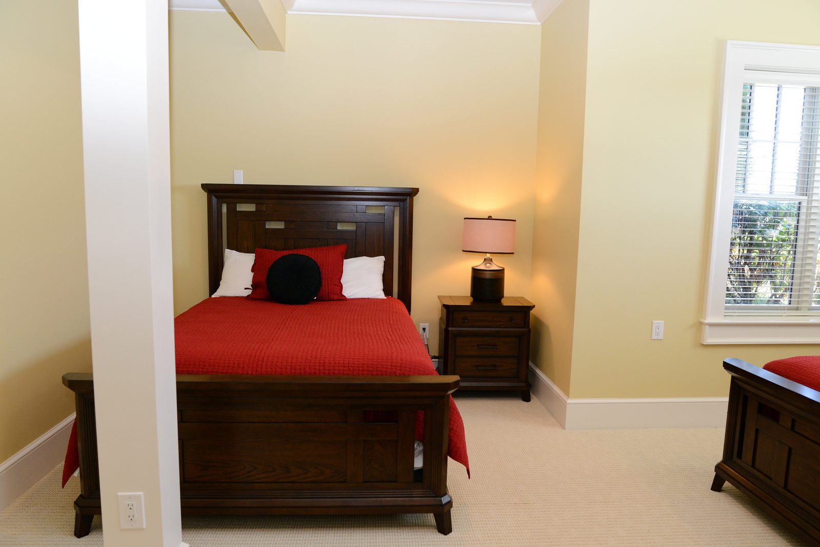 A guest room with red-linened beds, a column detail and a round area rug (view 4)