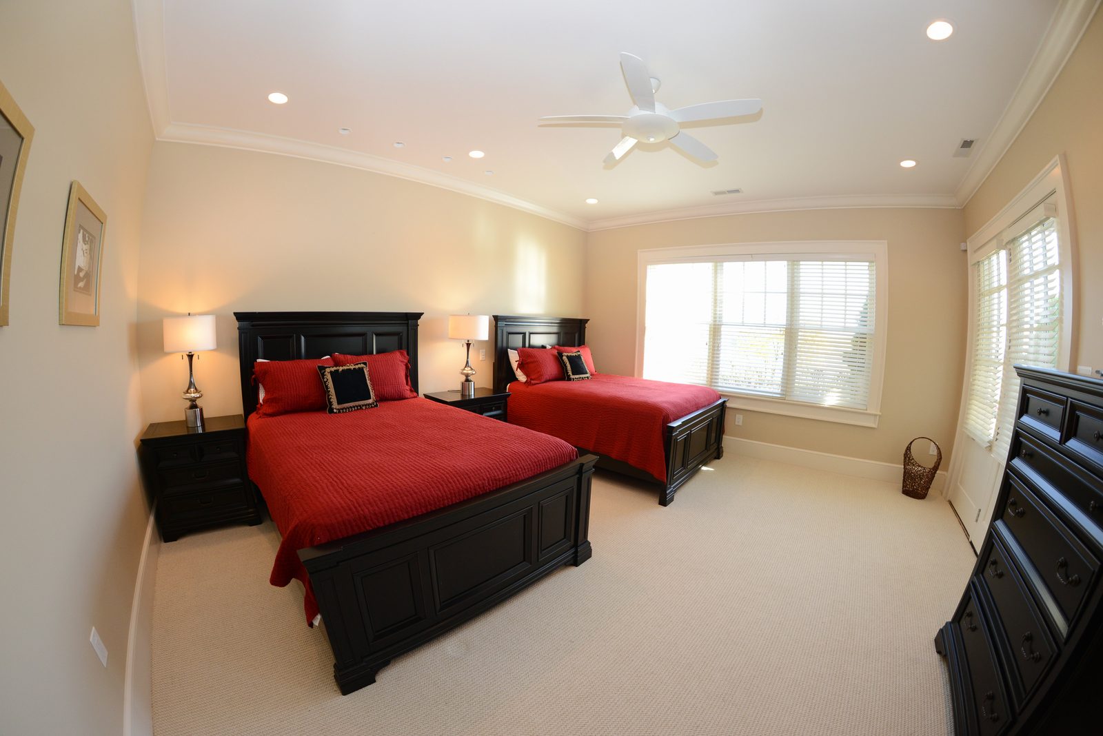 A guest room with two dark wood beds in red linens beneath a coffered ceiling (view 1)