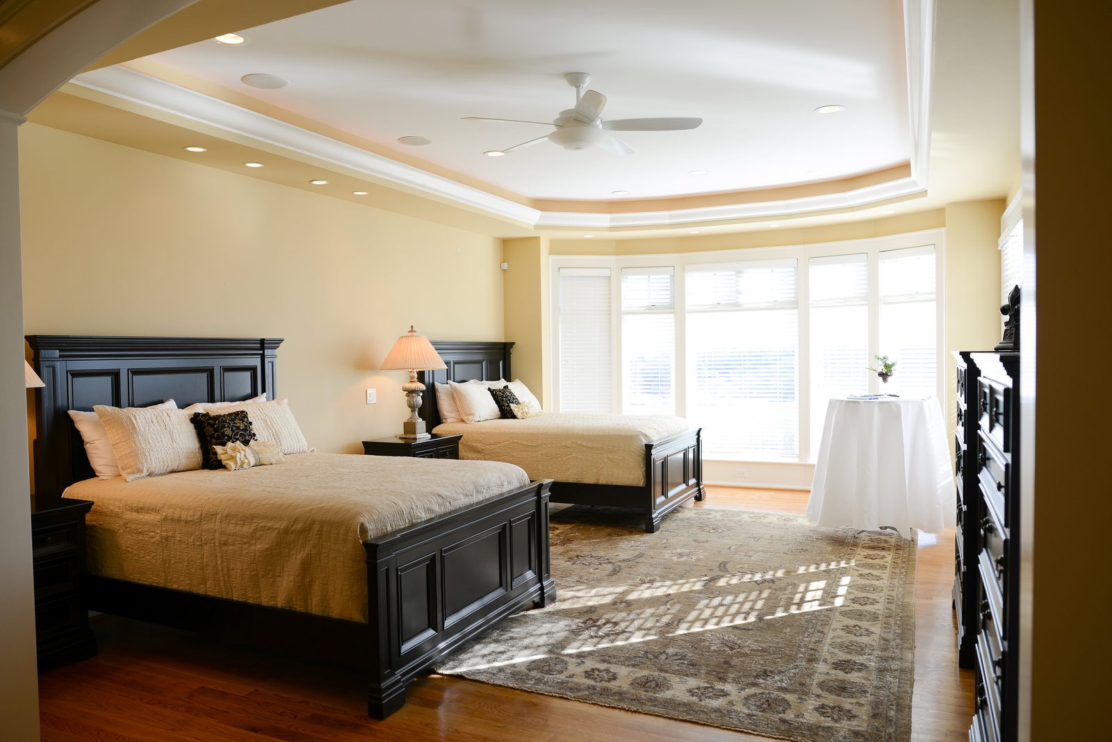 A guest room with two beds, patterned rug and a bay of windows