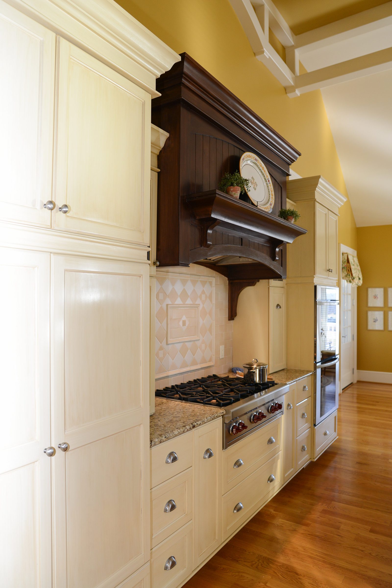 The main kitchen with cream cabinetry, a granite island and stainless appliances (view 1)