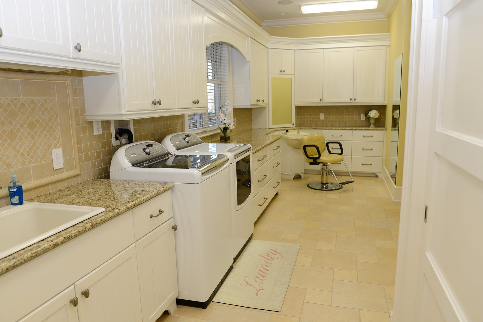 An on-site laundry room with a washer, dryer and folding counter