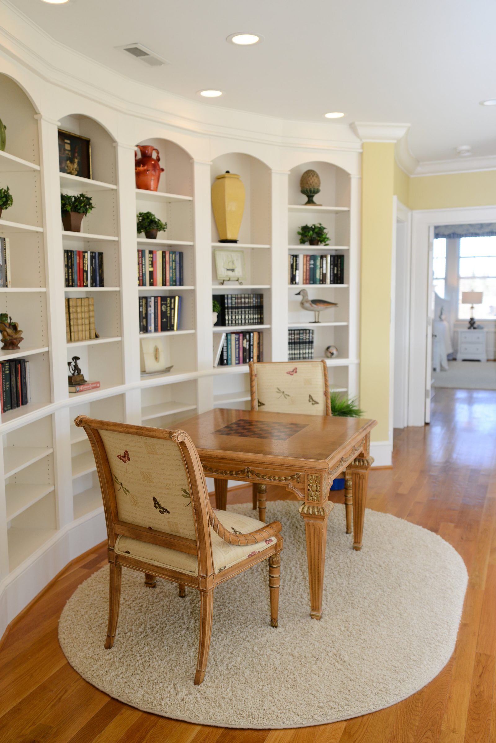 A library with floor-to-ceiling bookshelves and a wooden games table with two chairs (view 2)