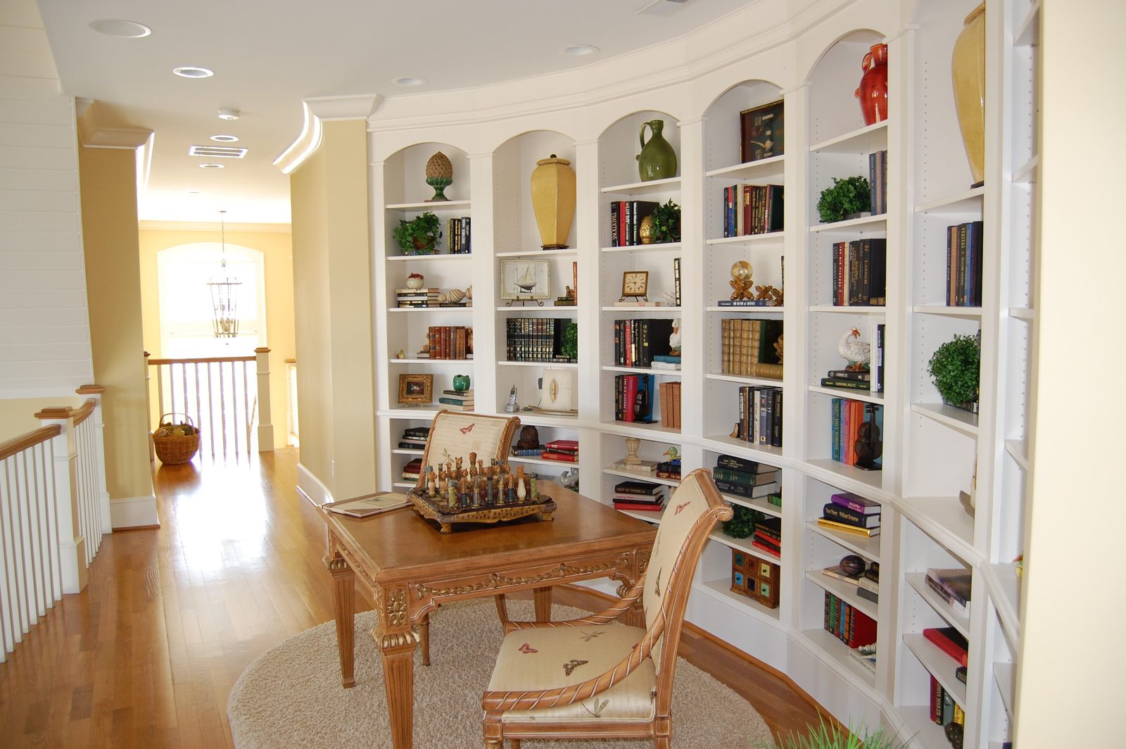 A hallway lined with built-in bookshelves and a small writing table
