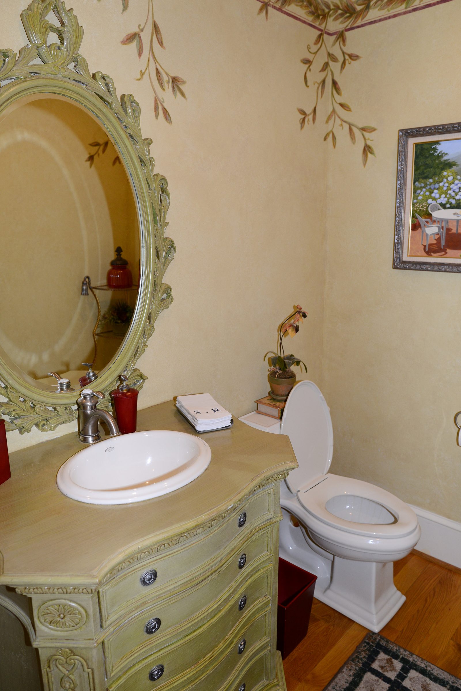 A powder room with a painted vintage vanity and a decorative mirror
