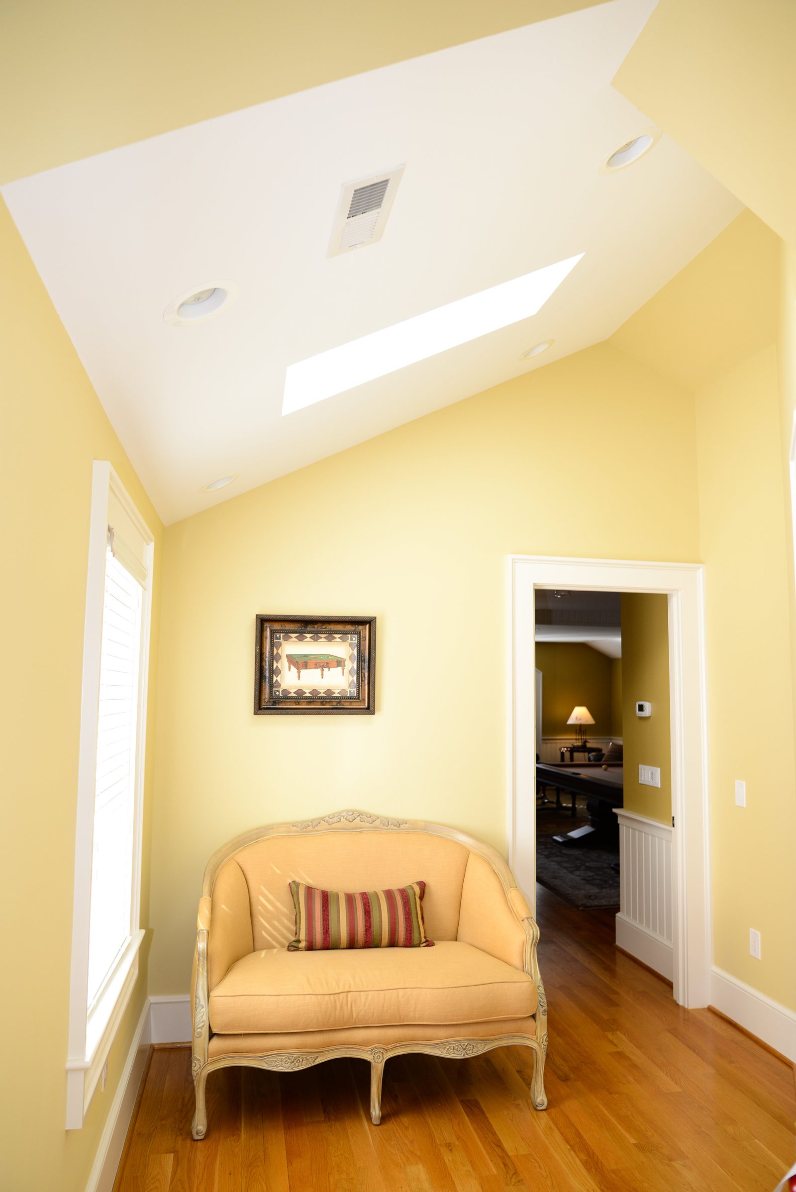 A quiet reading nook with an upholstered chair beneath a skylight (view 1)