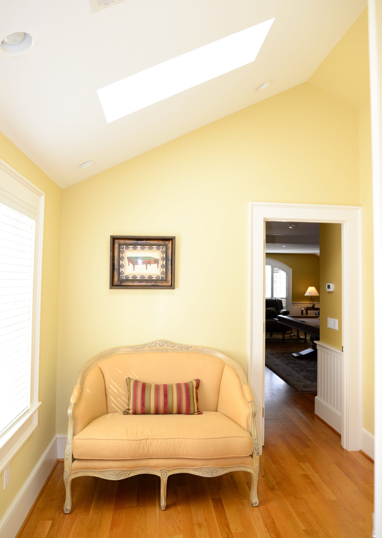 A quiet reading nook with an upholstered chair beneath a skylight (view 2)