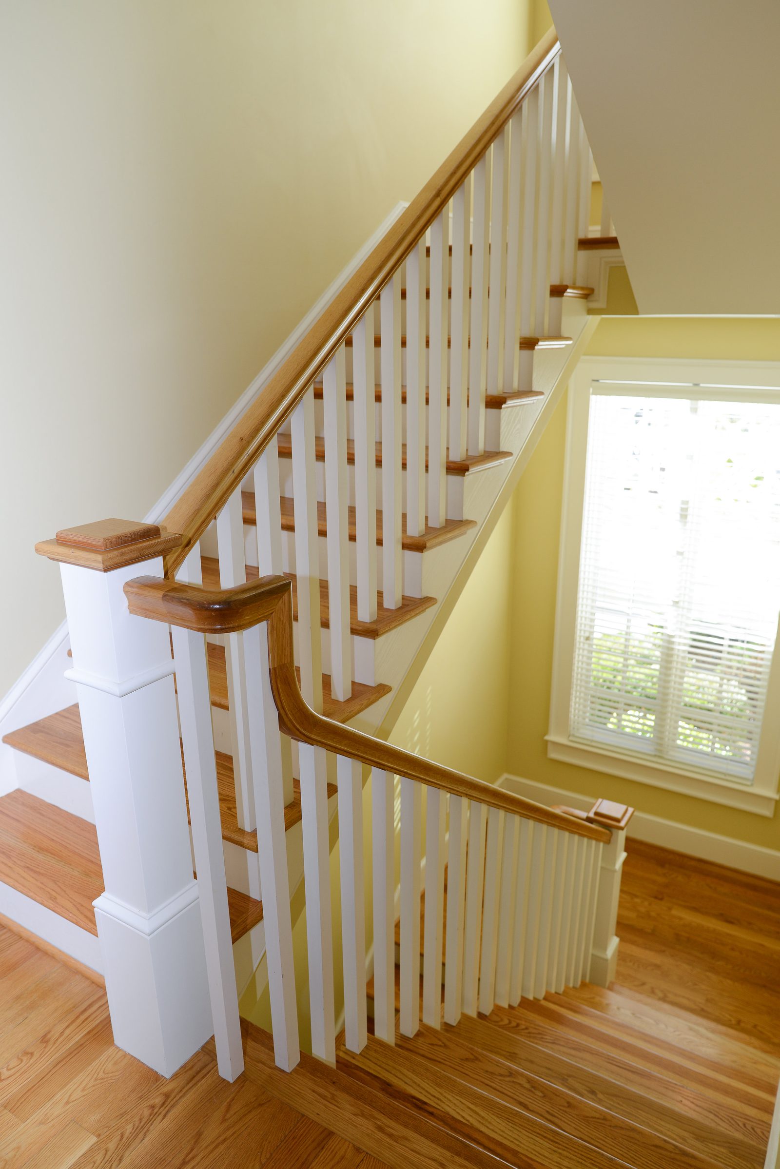 A hardwood staircase with a white banister rising to the upper floor