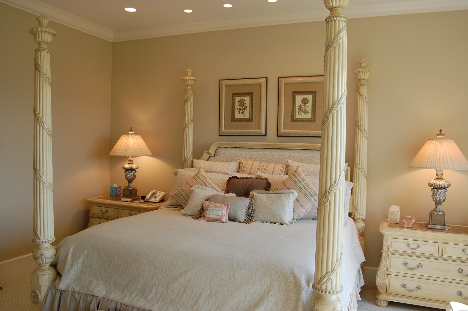 A suite with a four-poster bed, matching lamps and framed prints