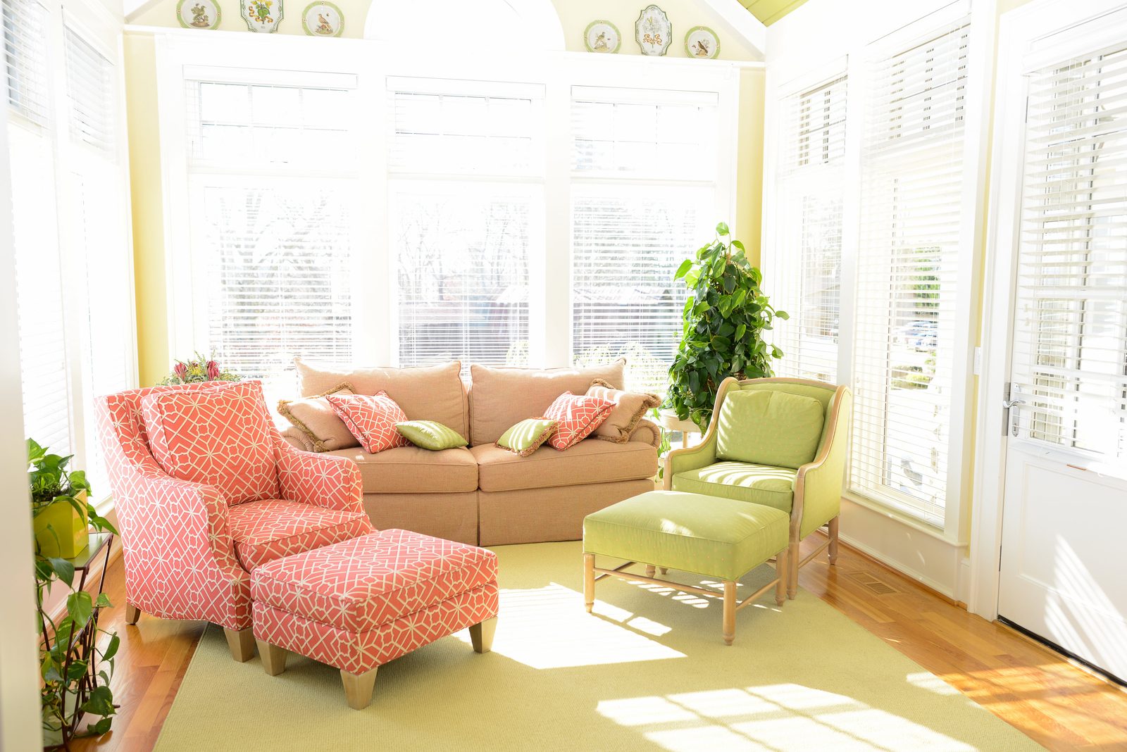 A sunroom with a sofa, patterned armchairs and windows on three sides (view 1)