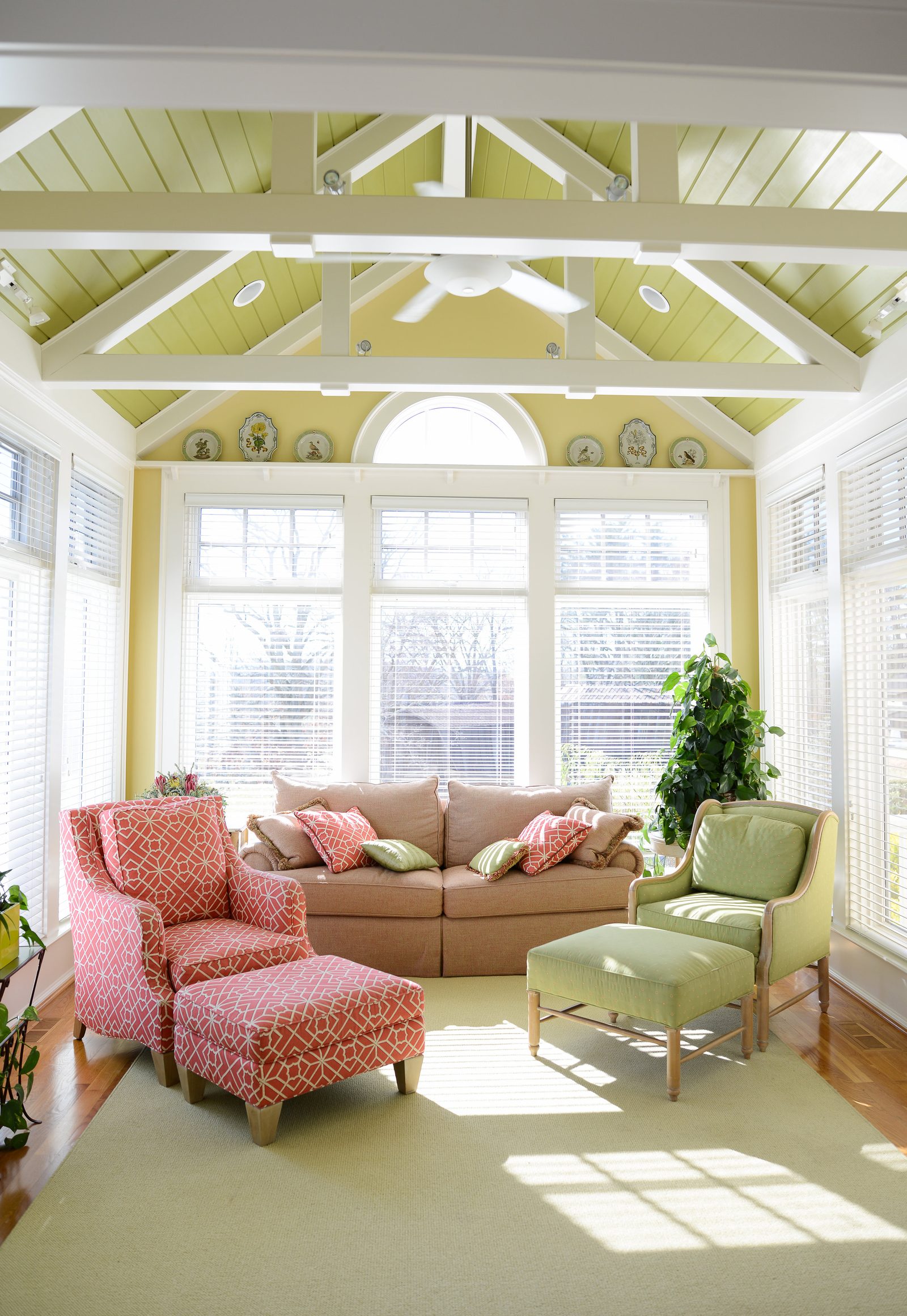 A sunroom with a sofa, patterned armchairs and windows on three sides (view 2)