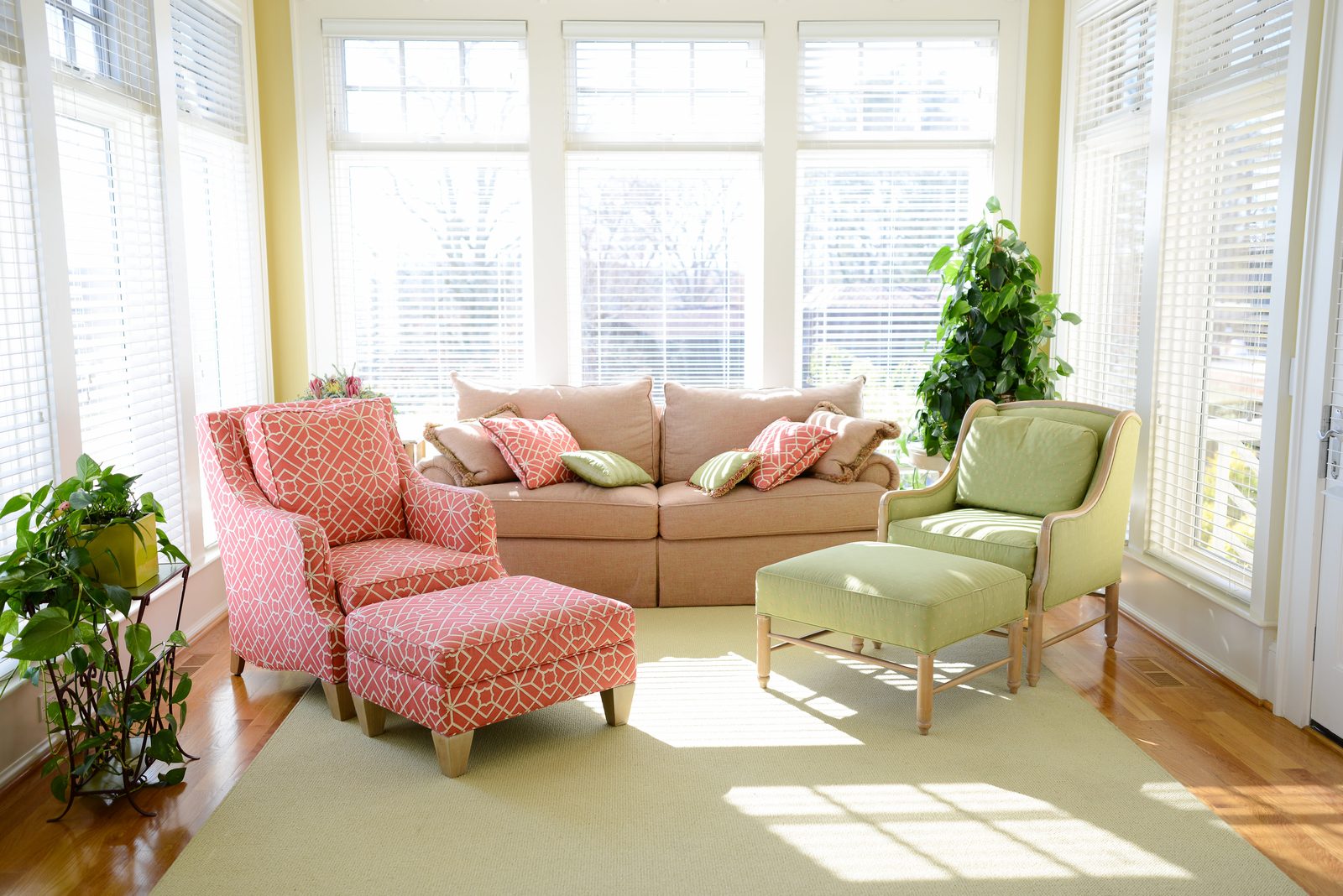 A sunroom with a sofa, patterned armchairs and windows on three sides (view 3)