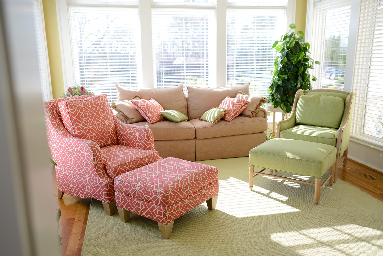 A sunroom with a sofa, patterned armchairs and windows on three sides (view 4)