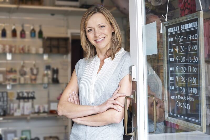 Female business owner smiling while looking out of her shop's walk up window