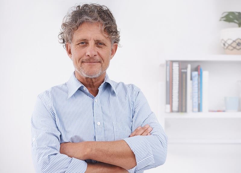Older caucasian man standing with his arms crossed