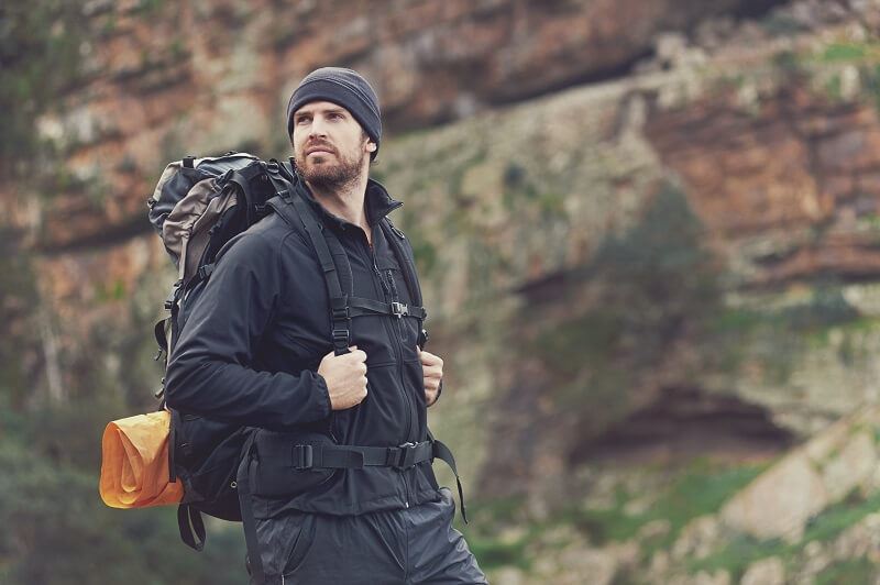 Caucasian male with hiking gear on hiking rocky terrain