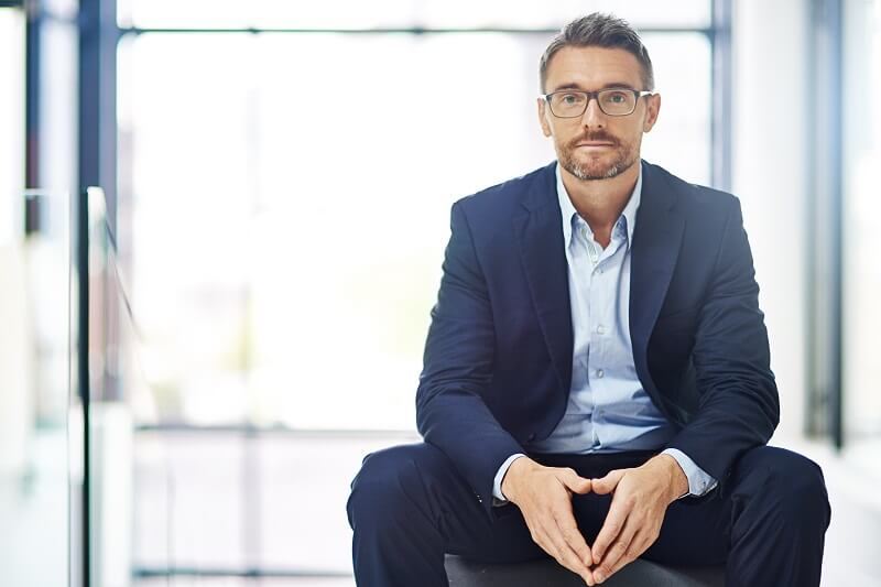 Adult businessman with glasses on looking at the camera