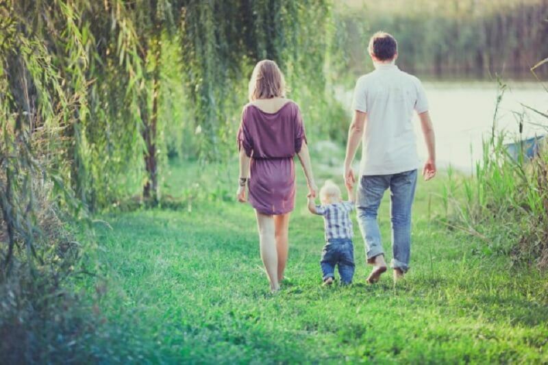 Young family walking down to the creek with their toddler