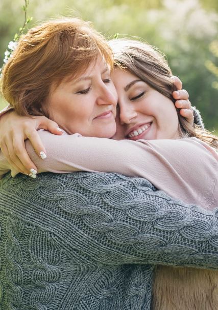 A caucasian mother hugging her teen/young adult daughter