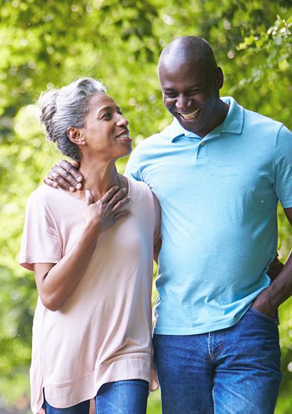 An older African American couple walking along talking with their arms around each other