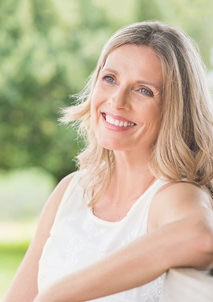 An adult woman with blonde hair looking off into the distance while smiling