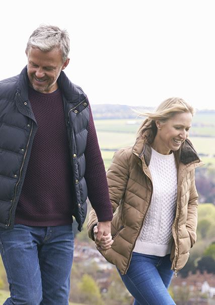 An older caucasian couple walking while holding hands